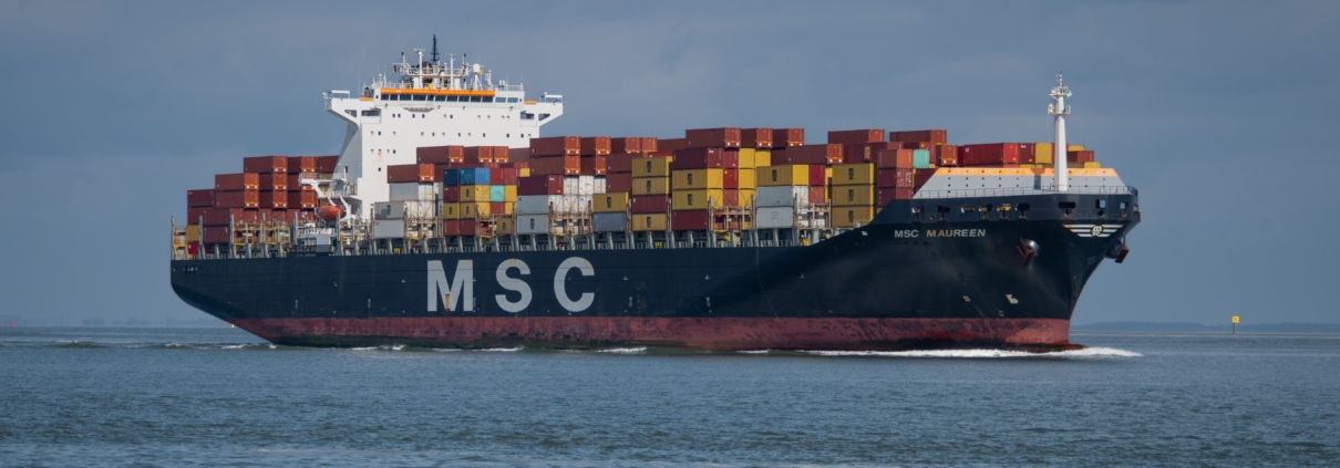 Das Bild zeigt ein Containerschiff beim Fahren auf dem Meer