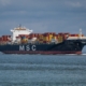 Das Bild zeigt ein Containerschiff beim Fahren auf dem Meer